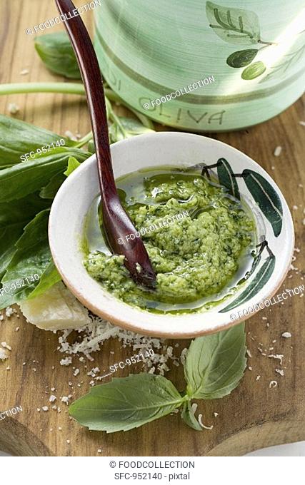 Pesto with olive oil in small bowl, basil, Parmesan