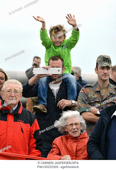 Family members of crew members of the frigate Augsburg wave during the frigate's return to the naval base in Wilhelmshaven, Germany, 14 July 2014