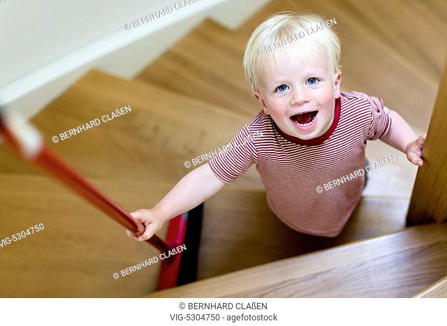 Germany , BARNSTEDT , 22.07.2015, Kleiner Junge, 2 Jahre, fegt eine Treppe mit einem Besen und freut sich. - Barnstedt, Germany, 22/07/2015
