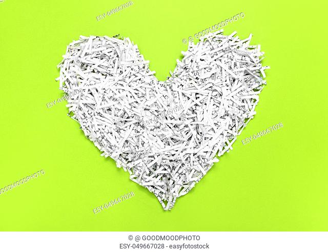 Heard made of shredded paper, on bright green background. Recycling concept