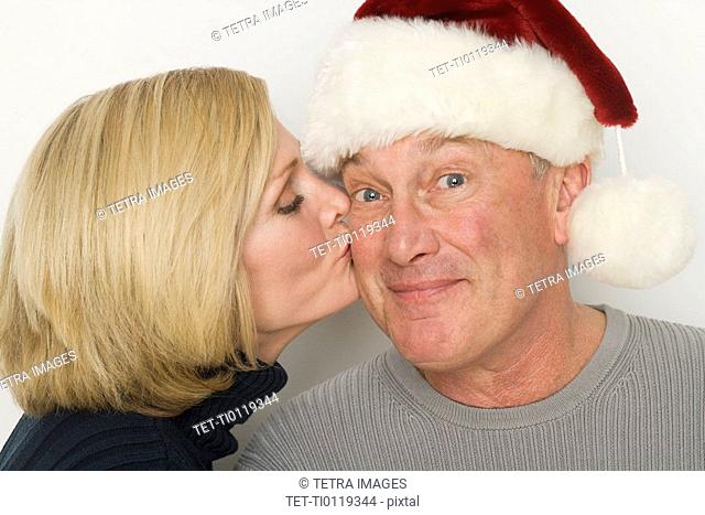 Woman kissing man with Santa hat