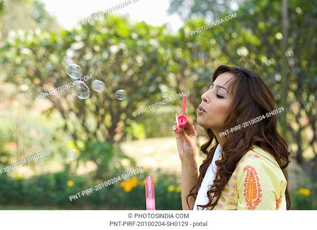 Woman blowing soap bubbles with a bubble wand