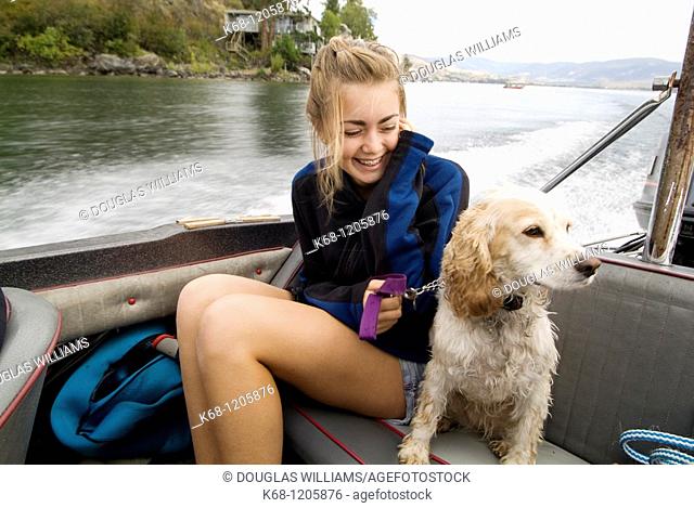 Girl with her Cocker Spaniel, in a boat on a lake