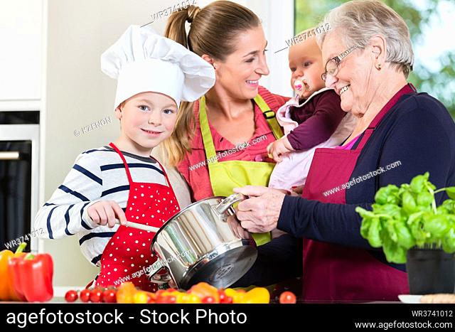 Mom, dad, granny and grandson together in kitchen preparing healthy food