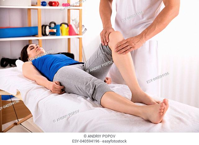 Woman Lying On Bed Receiving Leg Massage By Physiotherapist
