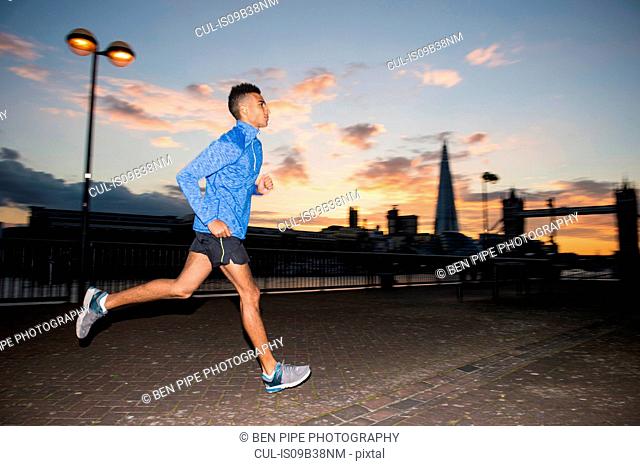 Man running, Tower Bridge and The Shard in background, Wapping, London, UK