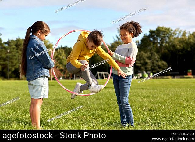 happy children jumping through hula hoop at park