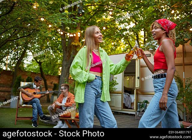 Little drunk two millennial females hugging and dancing together. Young adult people enjoying moment of carefree camping time on vacation