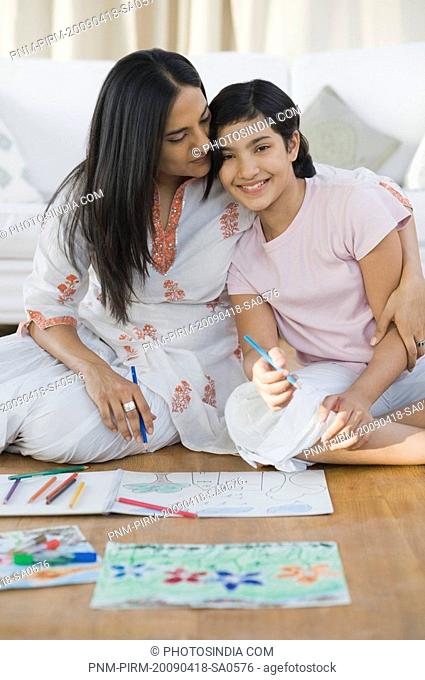 Girl making a drawing with her mother sitting beside her