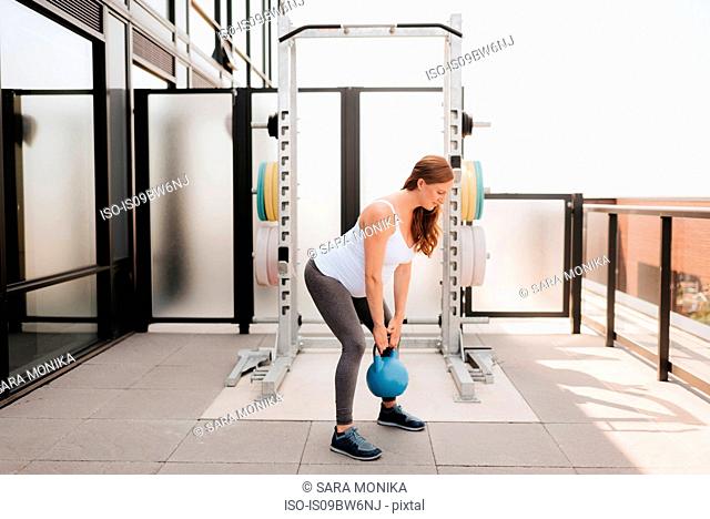 Pregnant woman exercising with kettle bell on balcony