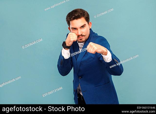 Dangerous man boxing at camera. Business people concept, richly and success. Indoor, studio shot on light blue background