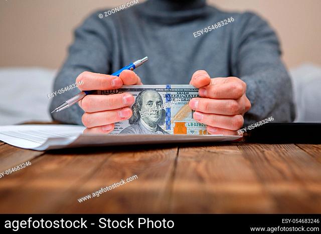 Caucasian hands counting dollar banknotes on dark wooden table