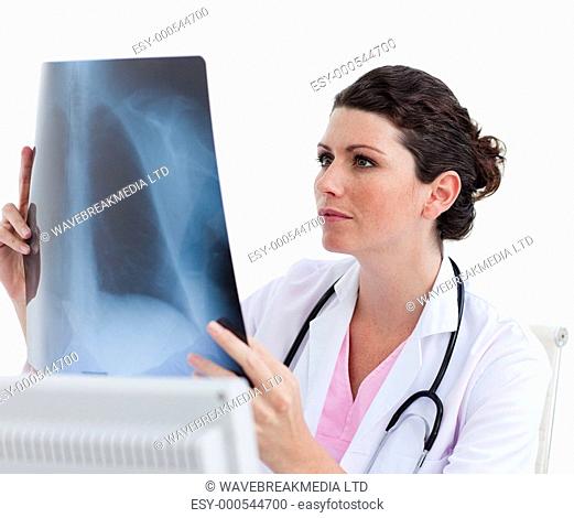 Pensive female doctor looking at X-ray in his office against a white background