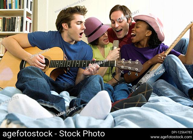 Two men and two women playing guitars in the bedroom