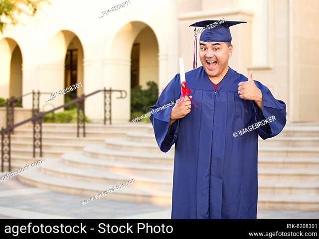 Hispanic male with deploma wearing graduation cap and gown on campus