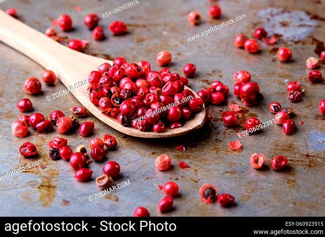 red color peppercorn seeds on steel plate with spoon