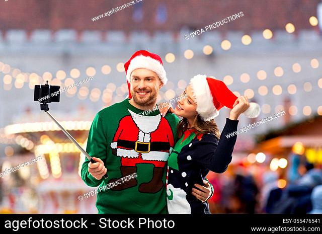 happy couple in christmas sweaters taking selfie