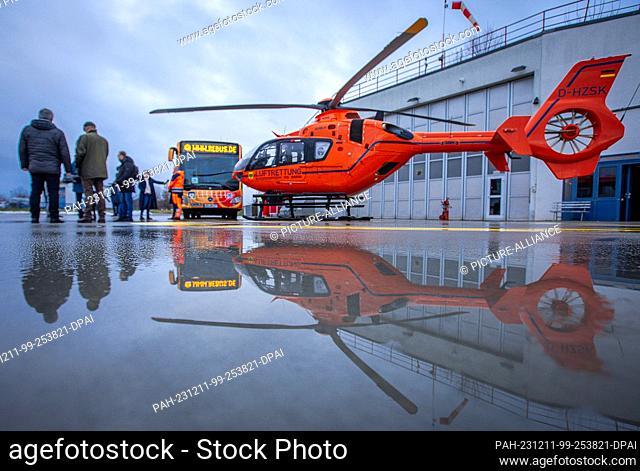 11 December 2023, Mecklenburg-Western Pomerania, Güstrow: A bus from the transport company Rebus and the rescue helicopter Christoph 34 are reflected in a...