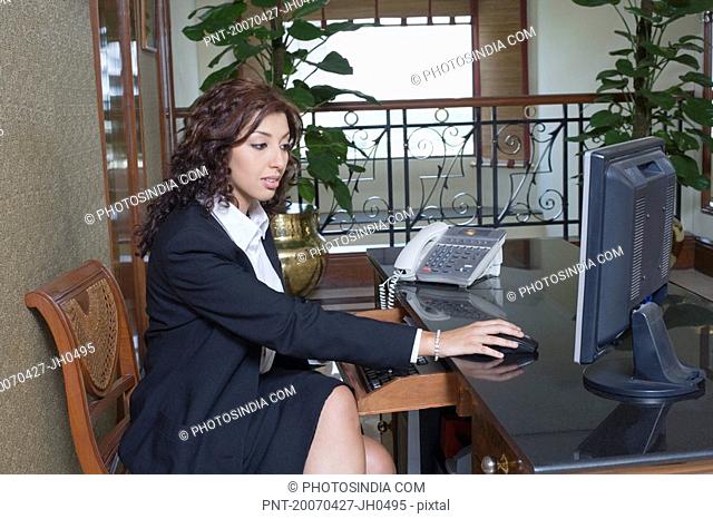 Side profile of a businesswoman sitting at a table and working on a computer
