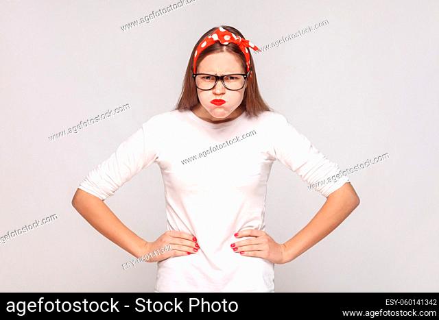 angry thinkful, raised hands. portrait of beautiful emotional young woman in white t-shirt with freckles, black glasses, red lips and head band