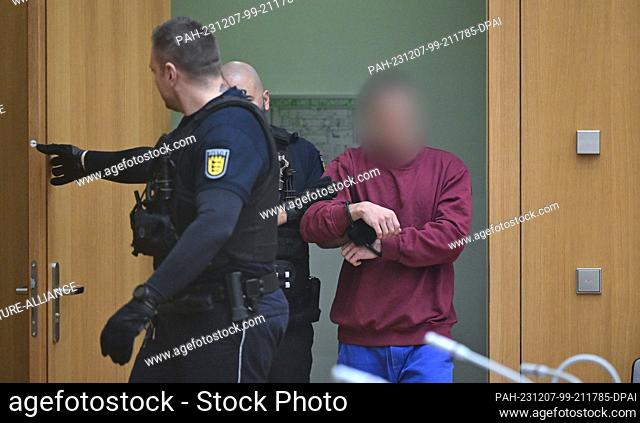 07 December 2023, Baden-Württemberg, Stuttgart: The defendant (r) enters the courtroom at the start of a trial for fifteen counts of attempted murder