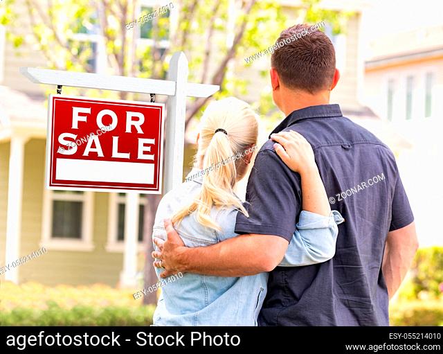 Caucasian Couple Facing Front of Sold Real Estate Sign and House