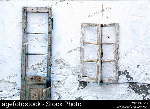 empty window frames hang on white house wall, greece