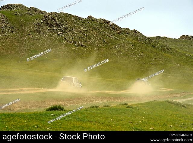 Zwei Geländewagen mit Touristen auf einer staubigen Naturstrasse, Orchon-Tal, Mongolei / Two four-wheel-drive vehicles with tourists on a dusty dirt road in the...