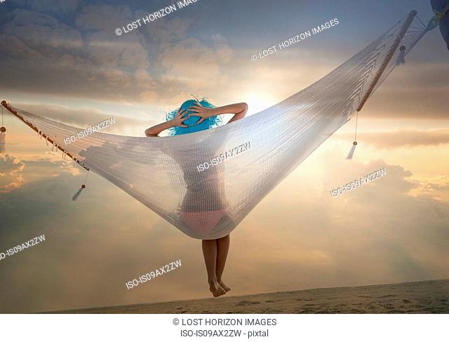 Rear view of young woman lying on hammock at sunset, Miami beach, Florida, USA