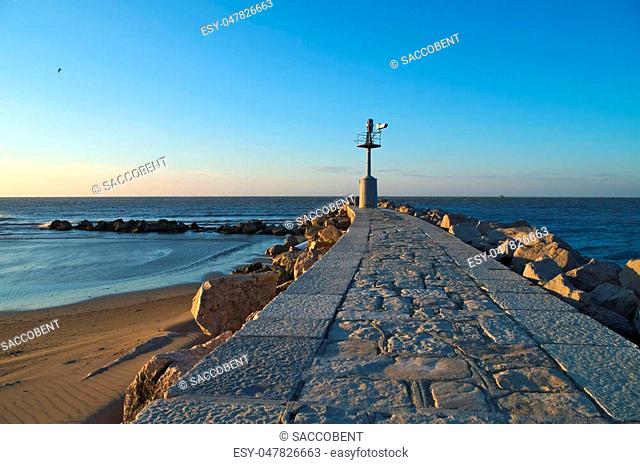 Sunrise on the old lighthouse on the breakwater of the village of Grado, Italy