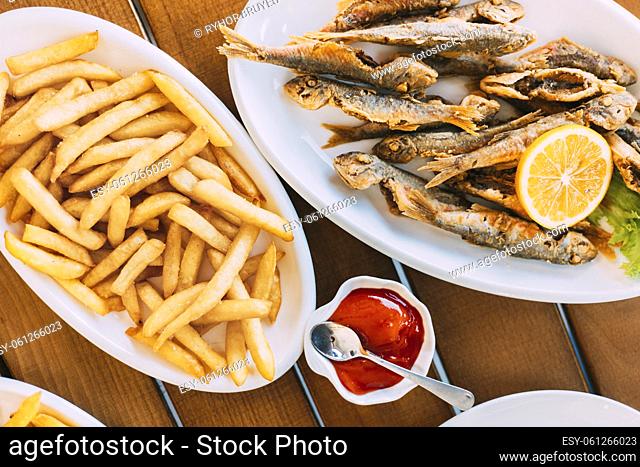 french fries and grilled fishes. fish and chips. Dish with Mullet Fish With orange. Fried fry small fishes