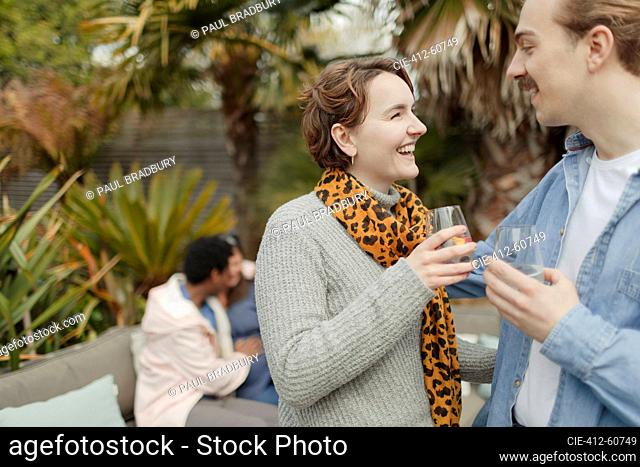 Happy young couple drinking and talking on patio