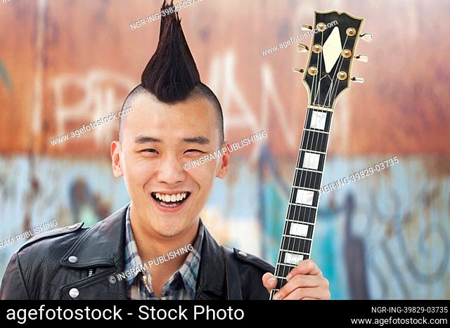 Young man with punk Mohawk holding guitar