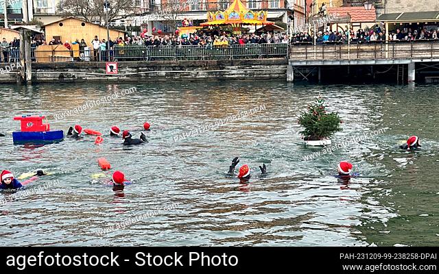 09 December 2023, Bavaria, Lindau (Bodensee): Onlookers watch the swimmers on the shore. On the Saturday after St. Nicholas Day, the now traditional St