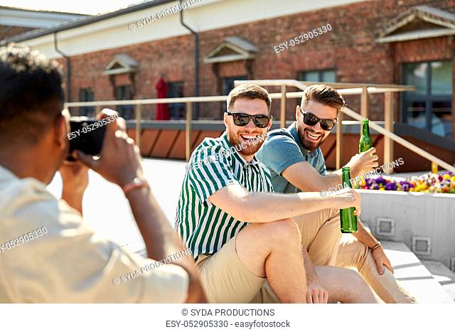 man photographing friends drinking beer on street