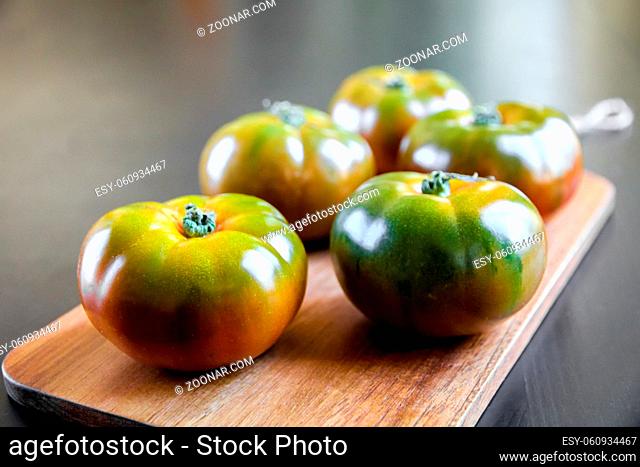Black Krim organic tomatoes on a wooden cutting board