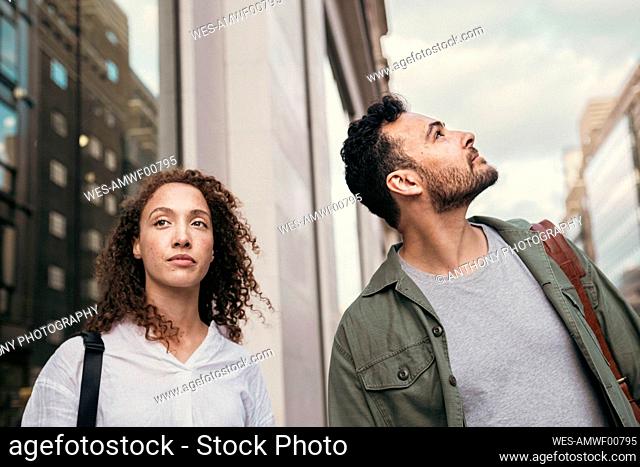 Contemplative woman standing by man looking up