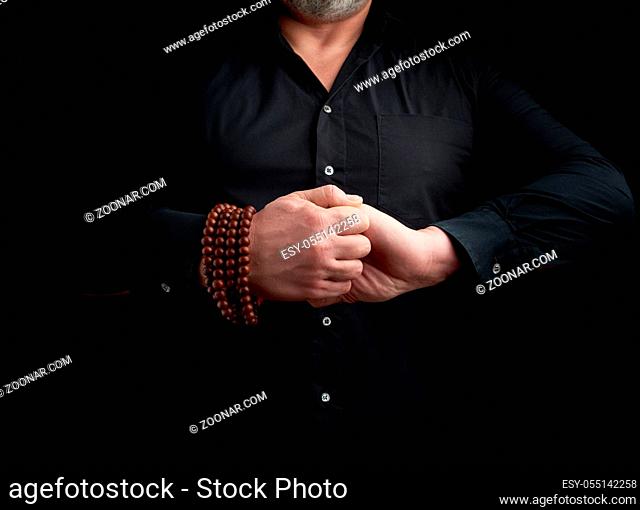 man in a black shirt crossed his arms in front of the torso, performing mudra, meditation