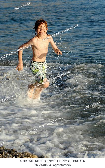 Boy running in the water on a beach by the sea