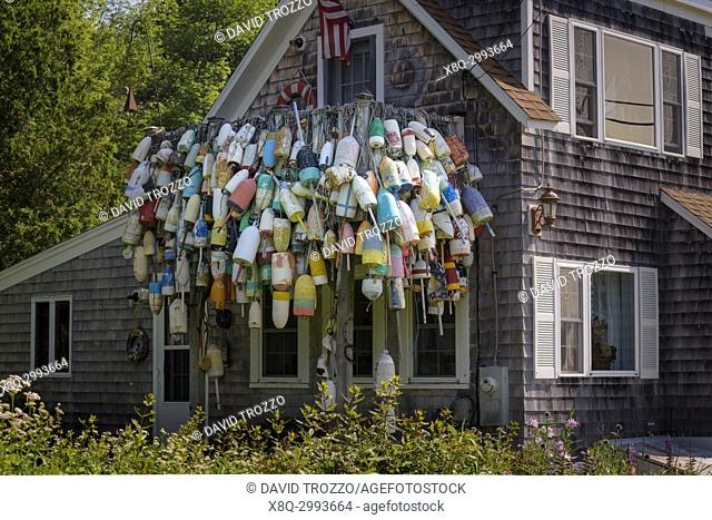 Old lobster bouys hang on a house in Spruce Head, Maine