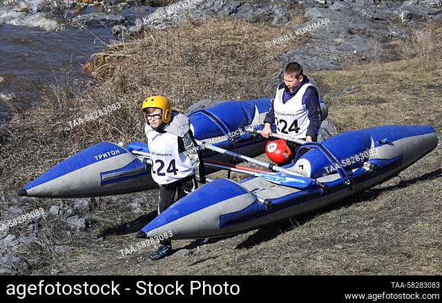 RUSSIA, NOVOSIBIRSK REGION - APRIL 7, 2023: Athletes carry a rafting catamaran during the 2023 Memorial Shabalina water-based tourism competition on the...