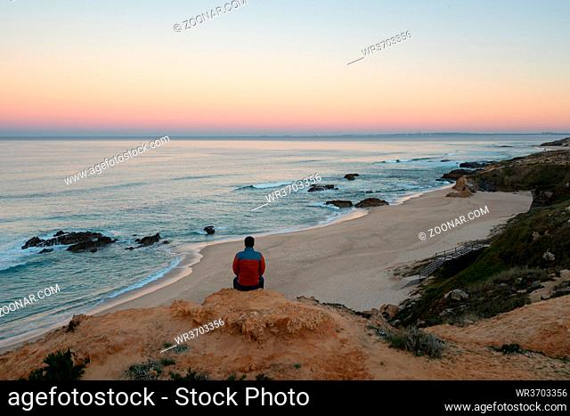Man seeing Praia do Malhao beach view at sunrise, in Portugal