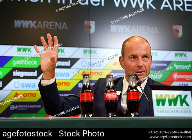 16 October 2023, Augsburg: Jess Thorup sits on the podium and raises his hand during his introduction as the new coach of FC Augsburg 1907