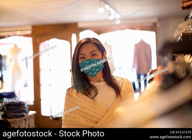 Portrait confident female shopper in face mask in clothing boutique