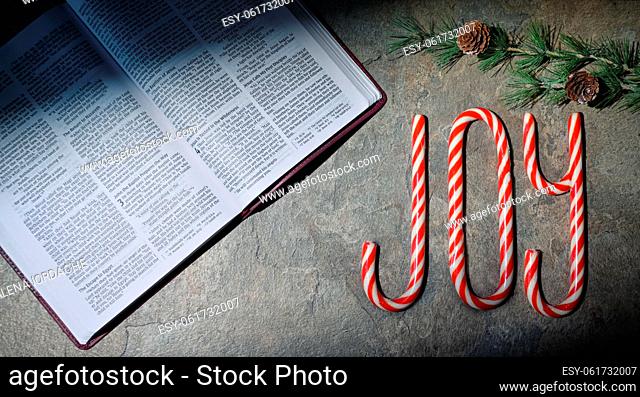 Open Bible and Joy Written With Candy Canes On Stone Table