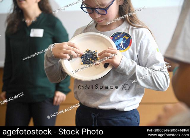 05 March 2020, Bavaria, Munich: A student of the Jules Verne Elementary School's team of schoolgirls holds an electronic component at a press conference in the...