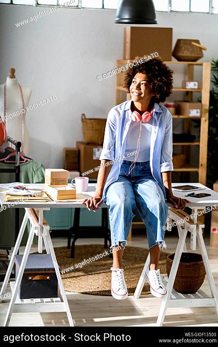Businesswoman looking away while sitting on desk at studio