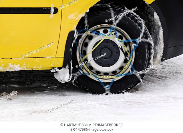 Yellow car driving with snow chains, detail of the rotating front wheel