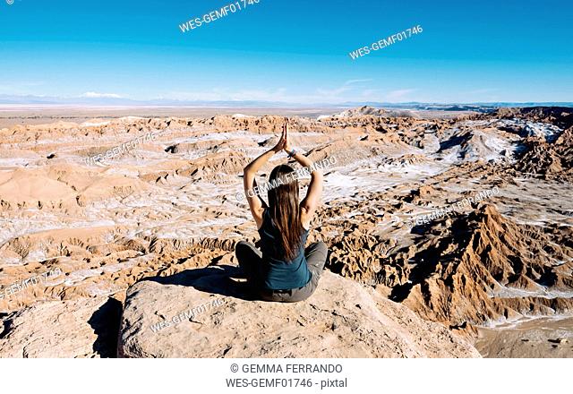 Chile, Atacama Desert, back view of woman practising yoga on a rock