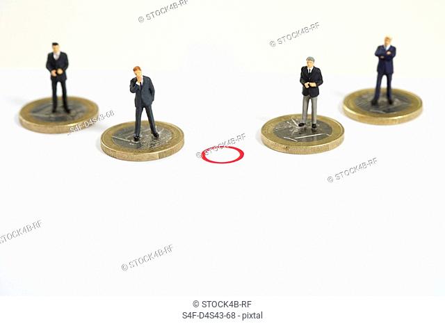 A red circle between businessmen figurines standing on Euro coins